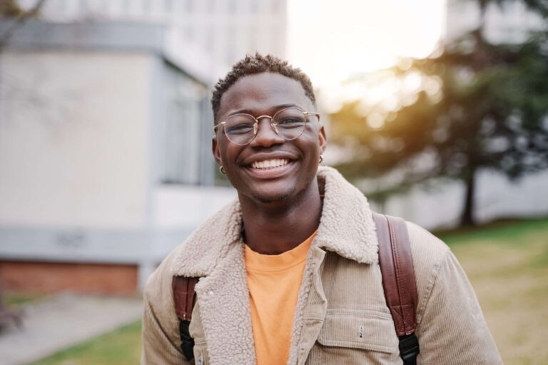 Um estudante segurando o certificado DALF diante de uma universidade estrangeira, simbolizando o início de sua jornada acadêmica no exterior.